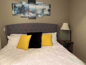 Relax in a serene space with a comfortable bed, a wall-mounted artwork, and a convenient nightstand.