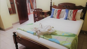 Una cama bien hecha con un edredón floral, cabecera de madera y almohadones decorativos.