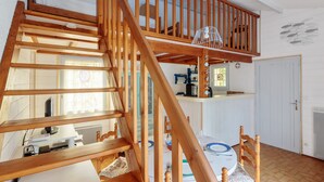 A wooden staircase leading to a loft bedroom with a kitchen area below. - Maison aux Oiseaux - Welkeys (Dolus-d'Oléron)