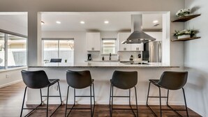 Una cocina moderna con una isla central, taburetes de bar y estanterías empotradas.
