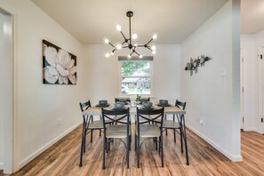 Un comedor con una lámpara de techo moderna, un amplio ventanal y una mesa de comedor dispuesta para seis comensales.