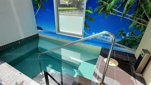 Een zwembad met een glazen barrière en een muurschildering van een strandlandschap.