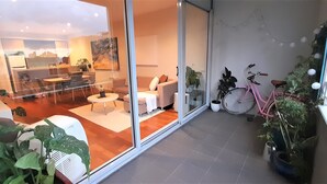 Een moderne woonkamer met een glazen scheidingswand, een roze fiets en potplanten.