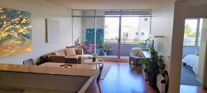 Relax in this spacious living area with a sofa, armchairs, and dining table, offering a view of the outside through the large window.
