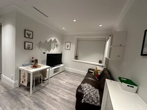 Ein modernes Wohnzimmer mit Fernseher, einem weißen Esstisch, einer schwarzen Ledersofa und einem Fenster mit Blick.