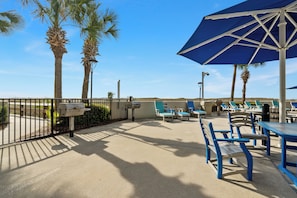 Relax in style with comfortable lounge chairs and tables amidst lush palm trees and a shaded area.