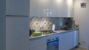 A modern kitchen with white cabinets, a gas stove, and a patterned backsplash. - Medusa - Ground floor apartment, a few steps from the sea and the center (Pineto)