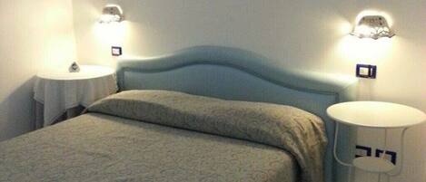 A bedroom with a bed, two bedside tables, and wall-mounted lamps.
