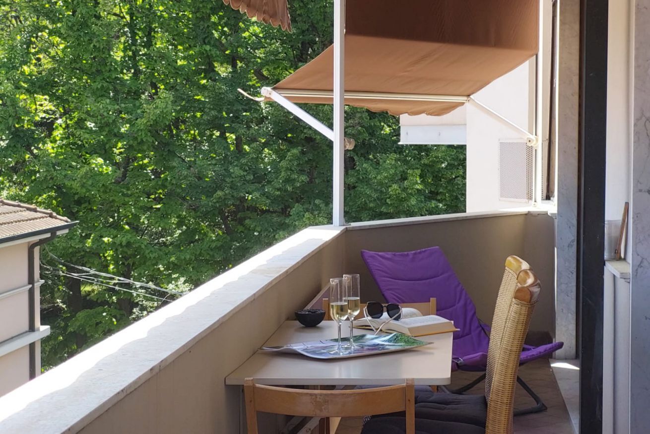 Un balcone con un tavolo, una sedia e un cuscino viola.