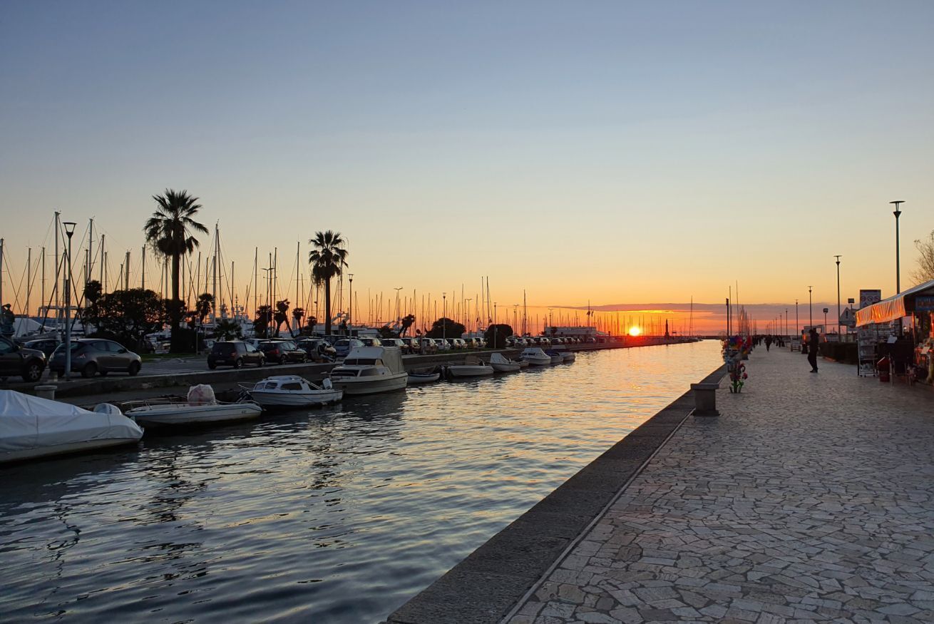 Una marina con imbarcazioni ormeggiate lungo un lungomare al tramonto.