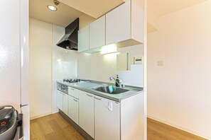 A modern kitchen with white cabinets, a stainless steel sink, and a built-in oven.