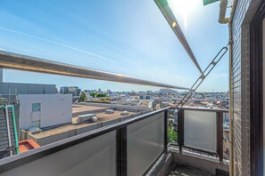 A rooftop view with a clear sky, a metal structure, and buildings in the distance.