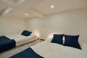 A hotel room with two beds, each with blue bedding and pillows.