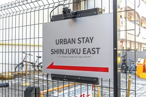A sign for 'URBAN STAY SHINJUKU EAST' with an arrow pointing to the right. - Grandioso Urban Stay Shinjuku East 20210 people4 / Shinjuku-ku Tokyo (Shinjuku-ku)