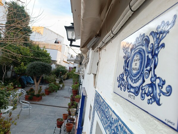 A narrow alley with potted plants and a white building with blue decorative tiles. - Typical and picturesque neighborhood courtyard, with charm, TRIANA (SEVILLA)