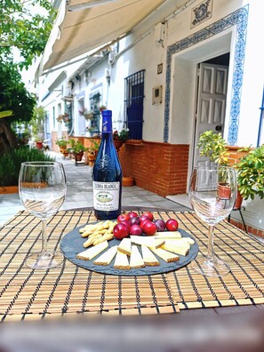 Una mesa con una botella de vino, copas y un plato de aperitivos.