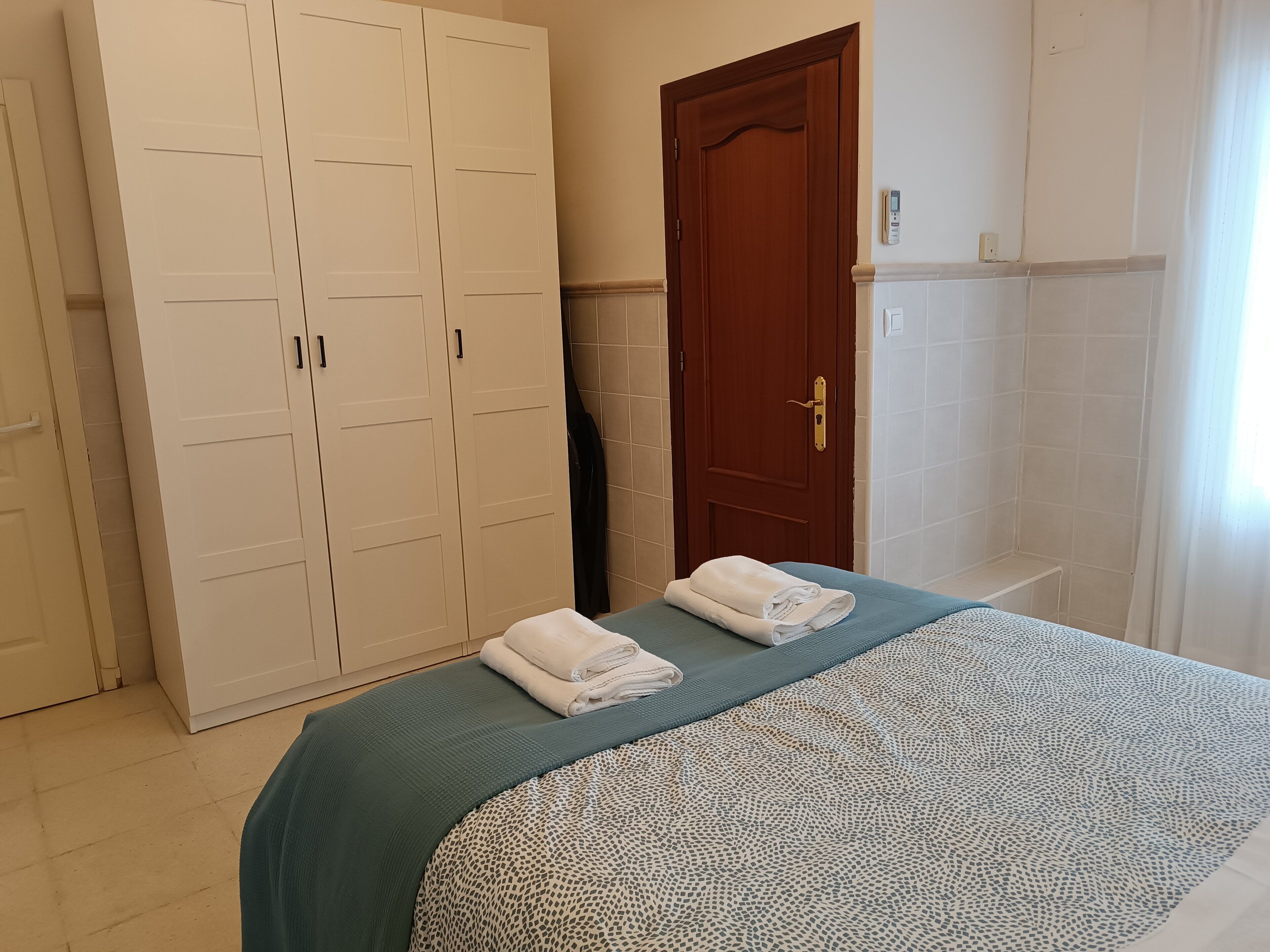 Una habitación de hotel con cama, armario, puerta y zona de ducha.