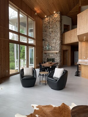 Un intérieur spacieux avec de grandes fenêtres, un mur en pierre et un plafond en bois.