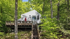 Une maison dotée d’une terrasse en bois et d’un escalier menant à un balcon situé à l’étage.