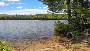 Un lac aux eaux cristallines, entouré d’une forêt dense et doté d’un quai en bois.