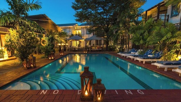 A swimming pool with lounge chairs and umbrellas, surrounded by palm trees and a brick pathway. - Protea Hotel by Marriott Dar es Salaam Oyster Bay (Dar es Salaam)