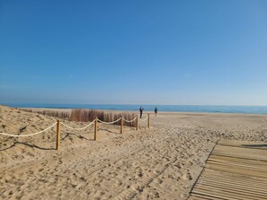 En sandstrand med en træpromenade og et rebstævne.