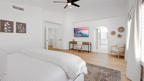 A spacious bedroom with a large bed, a desk, and a chair in the background. - Desert Sol l Heated Pool l Hot Tub l Putting Green (Scottsdale)
