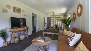 Een woonkamer met een televisie, bank, salontafel en decoratieve objecten.