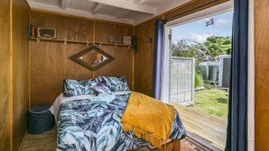 Un dormitorio con cama, cabecera de madera, espejo y vistas al exterior a través de una puerta corredera.