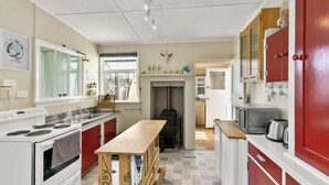Una cocina con estufa, lavamanos y mesa de madera.