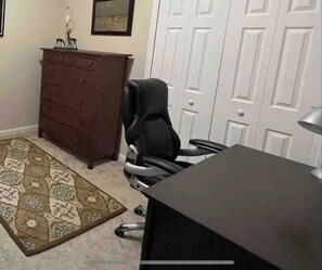 A room with a desk, a chair, a dresser, and a patterned rug. - Florida Beach & Theme Parks, Cozy Spa & Lake Views (Rockledge)