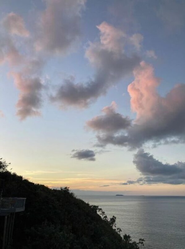 A coastal landscape with a clear sky, a body of water, and a hilly terrain.