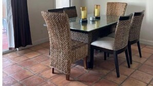 A dining area with a glass table surrounded by woven chairs, a chandelier, and framed artwork on the walls. - Ocean views from every room! (St Thomas)