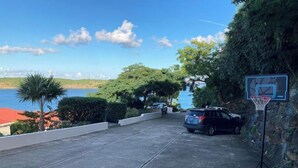 A parking area with a basketball hoop, a car, and a view of the sea. - Ocean views from every room! (St Thomas)