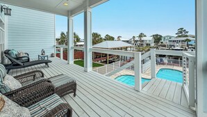 Eine überdachte Terrasse mit Gartenmöbeln, einem Pool und Blick auf Nachbarhäuser.