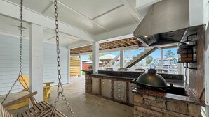 Ein überdachter Außenbereich mit Holzschaukel, Steintresen und Grillstation.