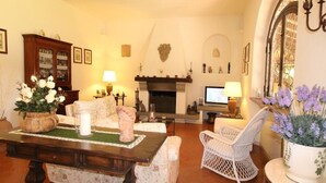 Una sala de estar acogedora con chimenea, arreglos florales y un área de descanso confortable.