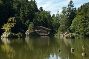Eine Lodge an einem See, umgeben von dichtem Wald.