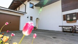 Une maison avec un garage, un patio couvert et un petit jardin agrémenté de tulipes.