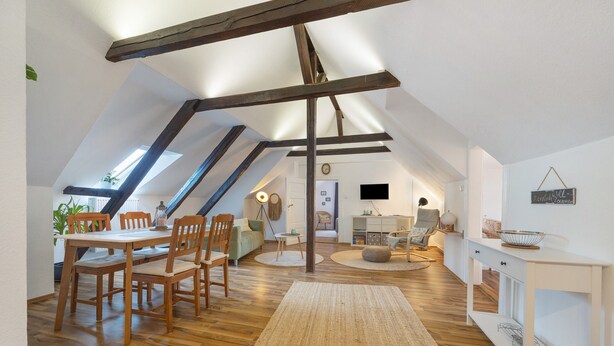 Un habitación estilo loft con comedor, un sofá, un televisor y una pizarra.