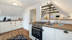 Una cocina moderna con armarios blancos, horno empotrado, lavabo y encimera de madera.