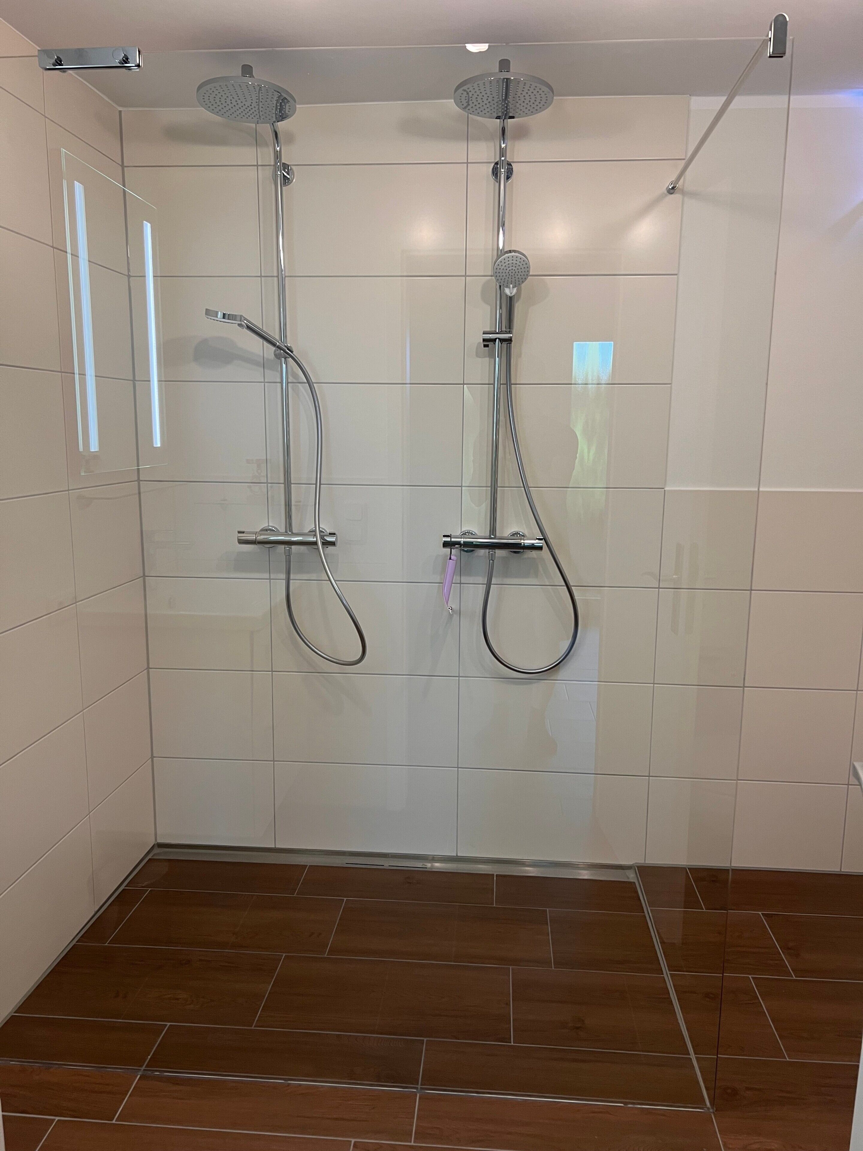 Et bruseområde med to brusehoveder i loftet og en håndbruser.