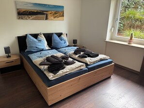 Une chambre moderne avec un cadre de lit en bois, une table de chevet avec une lampe et une fenêtre donnant sur un paysage verdoyant.
