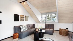 A modern living room with a sectional sofa, a round coffee table, and a large window. - Appartement with Balcony and Wi-Fi (Wangen im Allgäu)