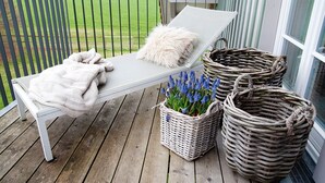A balcony with a white lounge chair, a white fluffy pillow, and two wicker baskets with blue flowers. - Appartement with Balcony and Wi-Fi (Wangen im Allgäu)