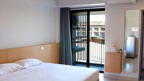 A hotel room with a bed, a desk with a telephone, and a view of the outside balcony. - Raveevan Hotel At Umong (Chiang Mai)