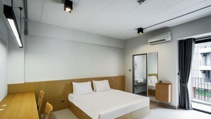 A modern hotel room with a wooden bed, a small desk, and a large window with a view of the outside. - Raveevan Hotel At Umong (Chiang Mai)