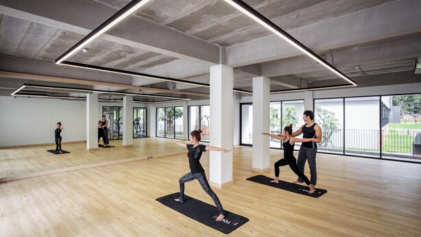 A spacious indoor gym with large windows, wooden floors, and modern lighting fixtures. - Raveevan Hotel At Umong (Chiang Mai)