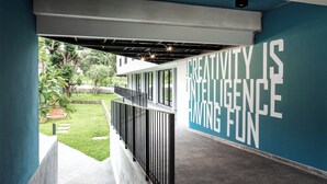 A modern building with a large outdoor area, a metal railing, and a wall with motivational text. - Raveevan Hotel At Umong (Chiang Mai)