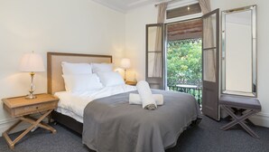 Un lit bien fait, avec du linge de lit blanc, une tête de lit en bois et deux lampes de chevet.